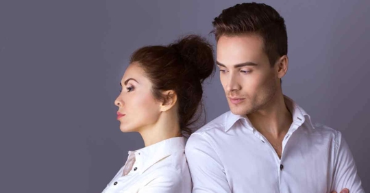 A man and woman standing back to back angrily against each other.