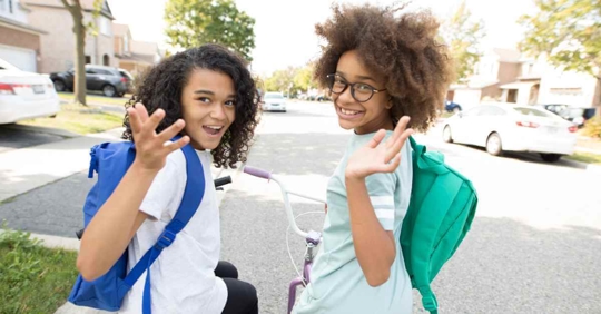 Two girls waving as they walk back to school