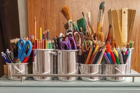 Various art supplies stored in silver canisters.