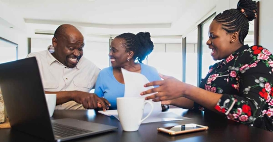 A couple smiling as they sit with an attorney going over an estate plan and various documents