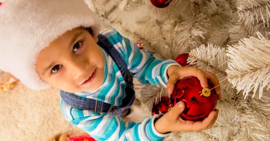 A young child holding a red ball ornament
