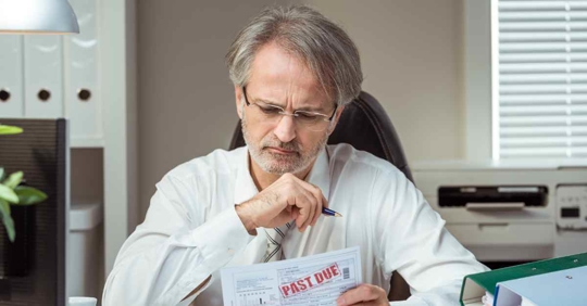 A man looking at a bill that reads "past due"