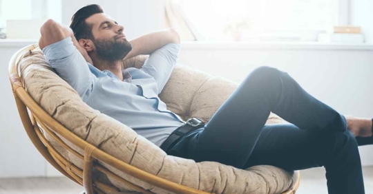 A man relaxing in a comfortable chair. He has a slight smile on his face.