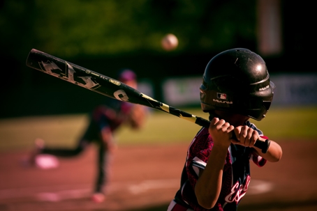 Young boy holds bat and prepares to swing while playing baseball