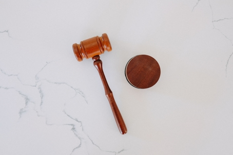 A wood gavel sits on a white marble table.
