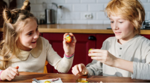 Two children sitting at a table and smiling while playing together, representing shared parenting time and child custody arrangements.